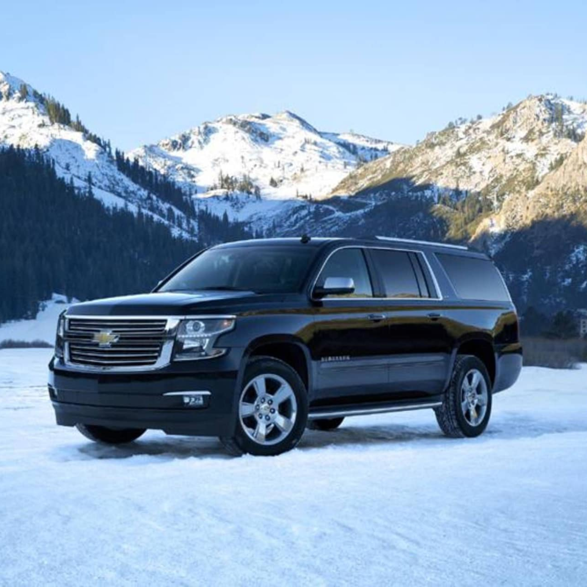 Black SUV on snowy terrain with mountains in the background.